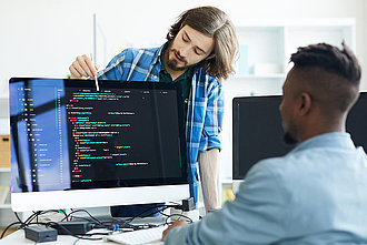 2 Männer schauen einen Computer-Code an